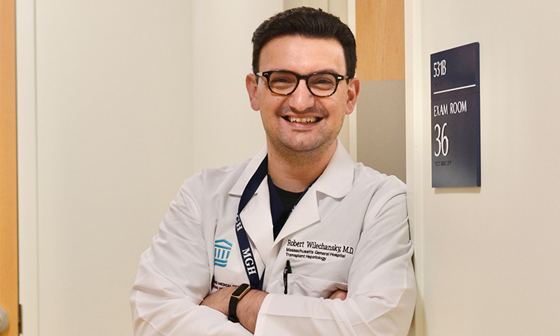 male fellow in lab coat smiling in hallway